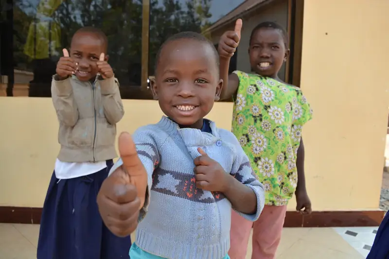 Children grinning and giving a thumbs up