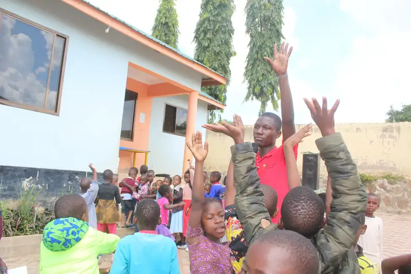 A CarePoint worker with children raising their hands