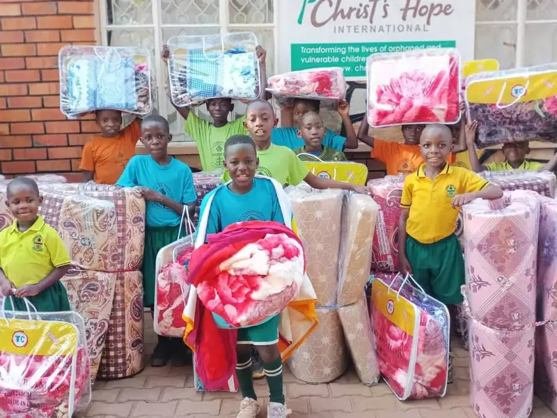 Children at a CarePoint holding new mattresses and blankets
